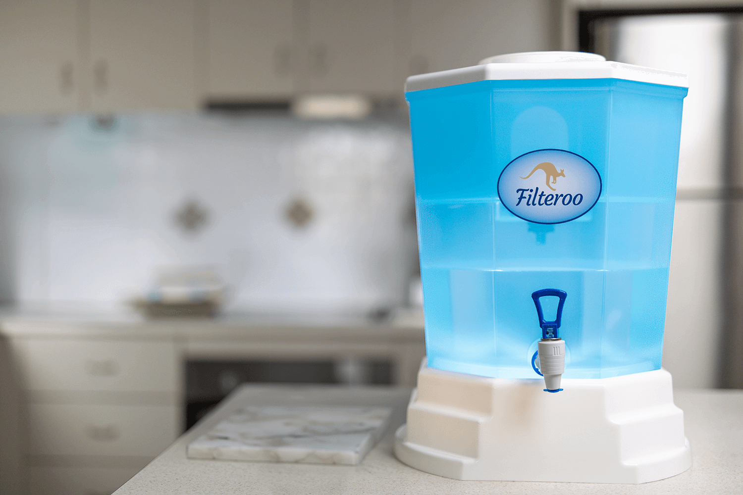 A Filteroo Blue Tap gravity water filter with a sleek white base sits prominently on the kitchen counter.