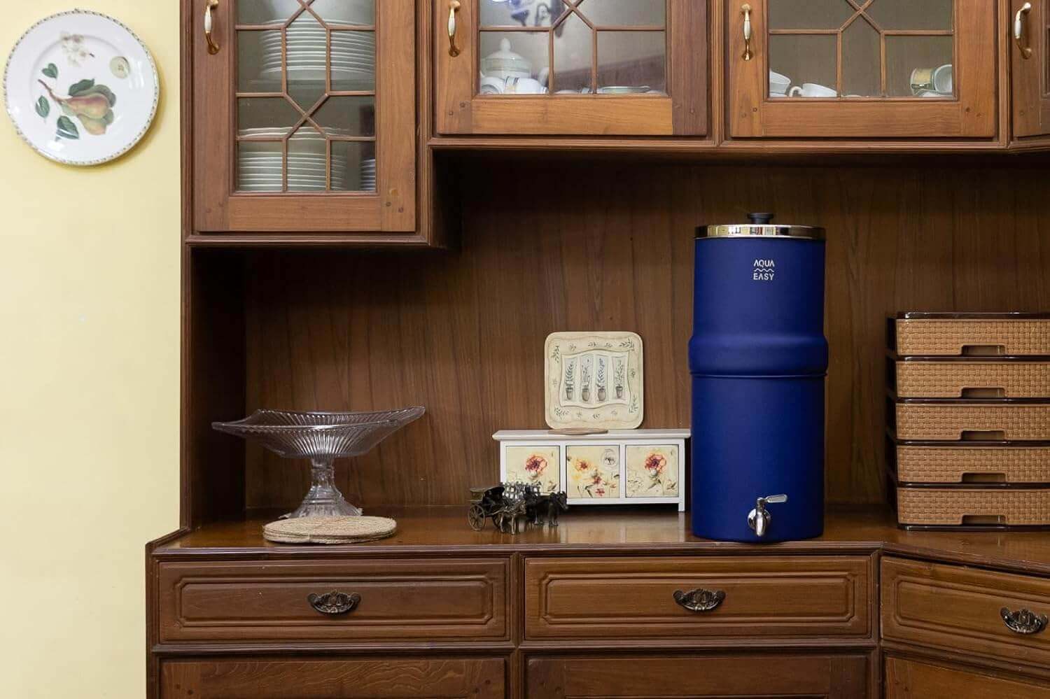 The blue AquaEasy Stainless Steel Gravity Water Filter System displayed on a kitchen cabinet