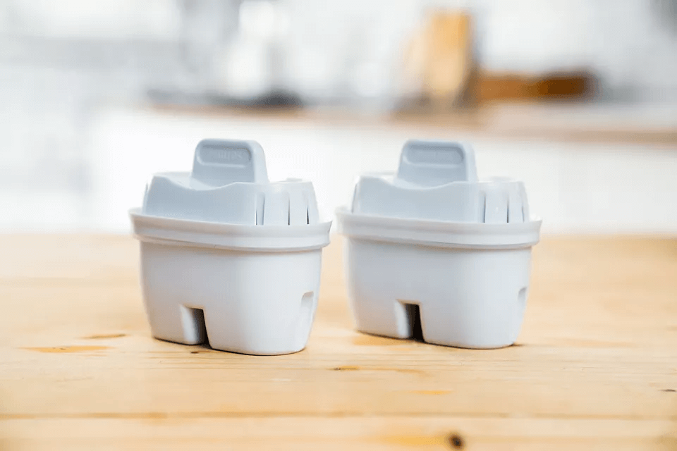 Two Philips Micro X-Clean carbon filter cartridges from the AWP211 set stand on a wooden surface