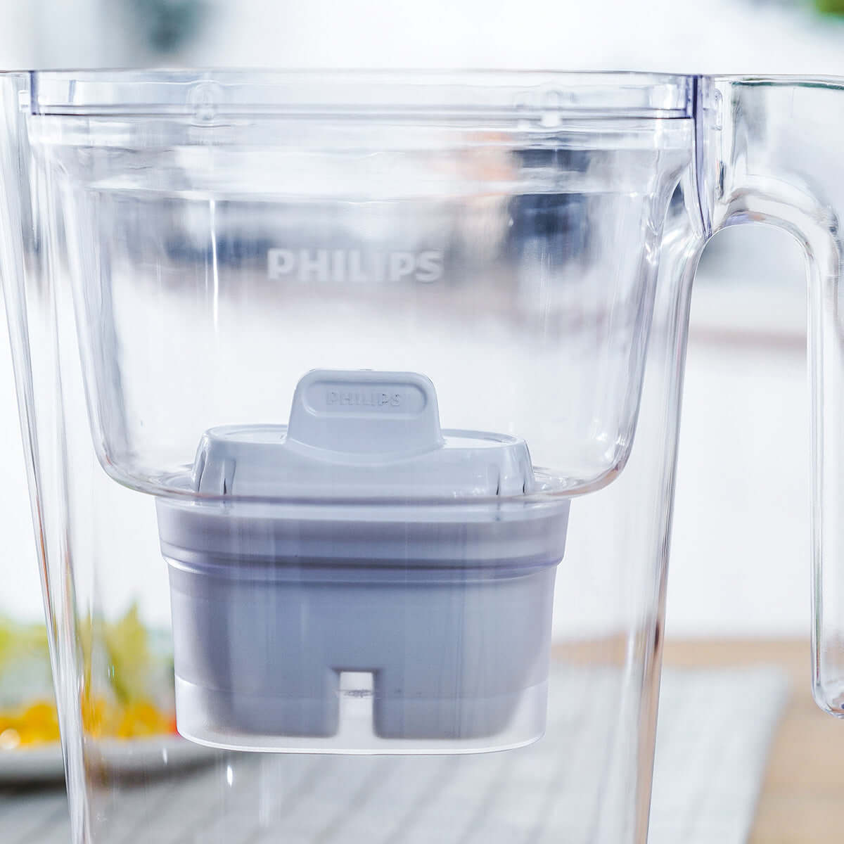 Close-up of a clear water pitcher with a Philips Micro X-Clean Carbon Filter AWP211 cartridge from the 12-pack inside.