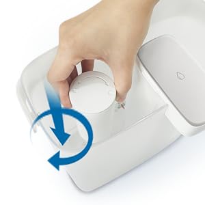A hand inserting a Philips Micro X-Clean Filter AWP225/79 cartridge into a rectangular device, with a blue arrow showing a clockwise twist on the Philips Instant Water Filter.