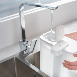 Close-up of a Philips Micro X-Clean Filter AWP225/79 poured with water into a white pitcher from a kitchen faucet.