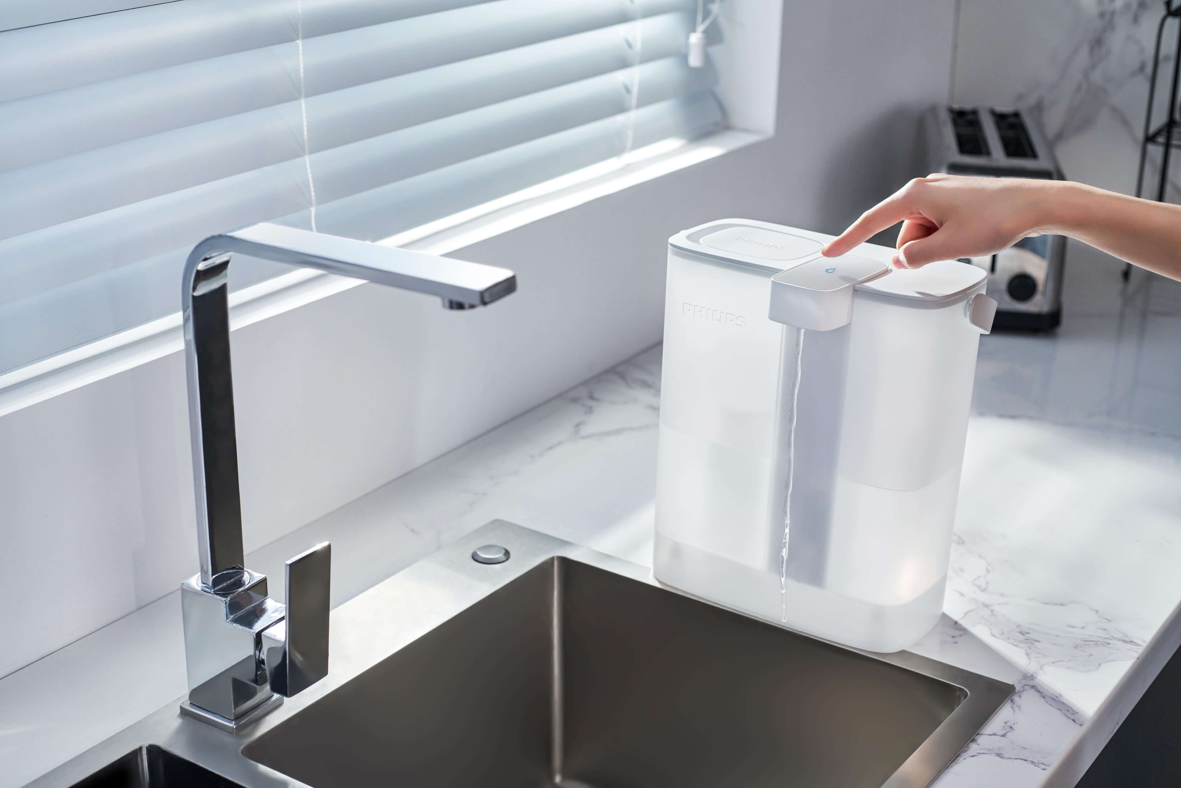 An individual is utilizing the Philips Next-generation instant water filter AWP2980WH with Micro X-Clean instant filtration technology at a modern kitchen sink.