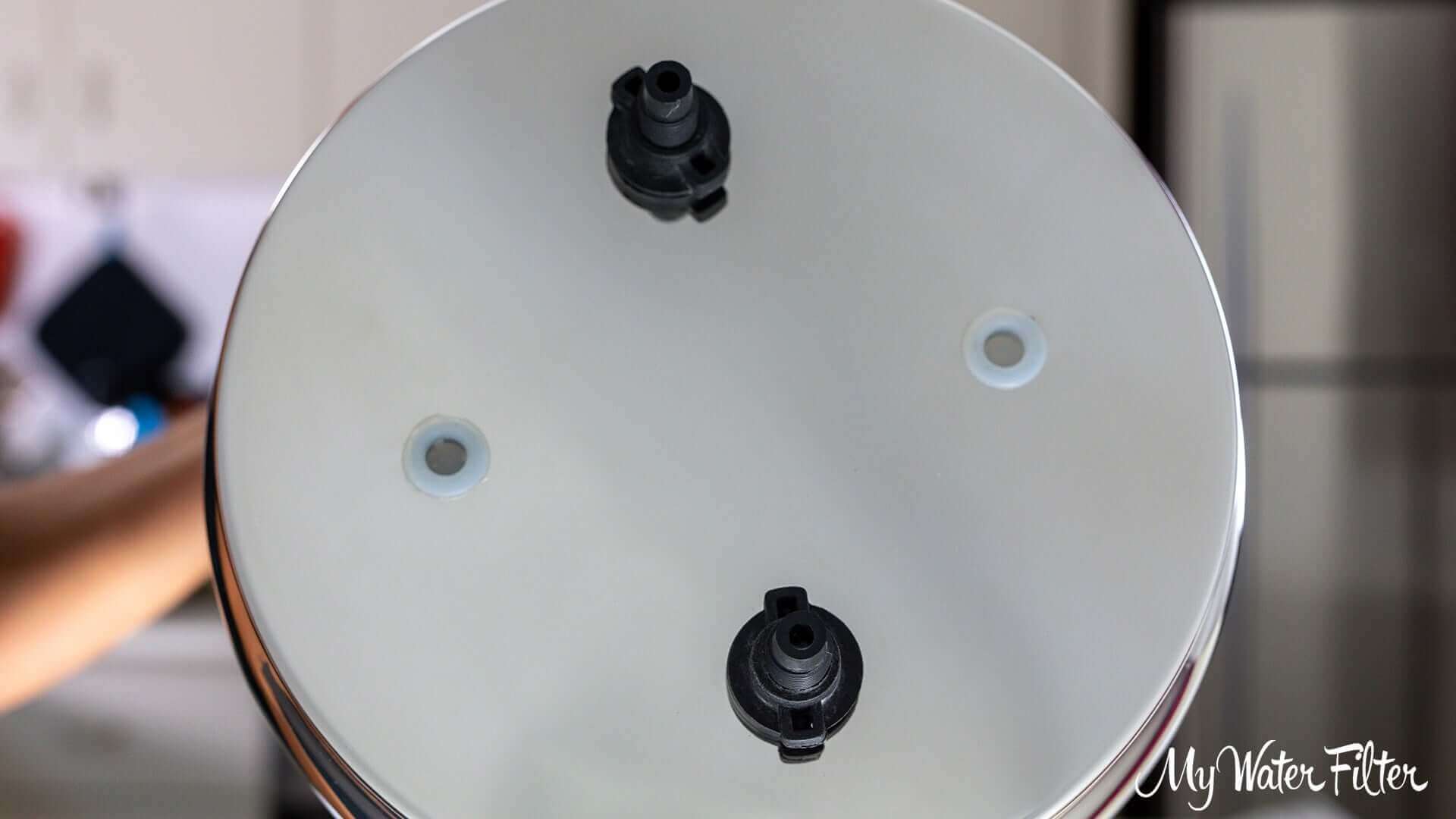 The underside of the Phoenix Stainless Steel Gravity Water Filter top tank features a round design with four holes, 2 of which are inserted with wing nut