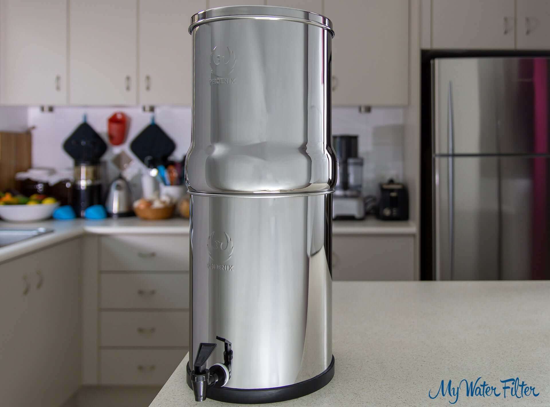 A Phoenix Stainless Steel Gravity Water Filter positioned in a kitchen setting, featuring a faucet at the bottom.