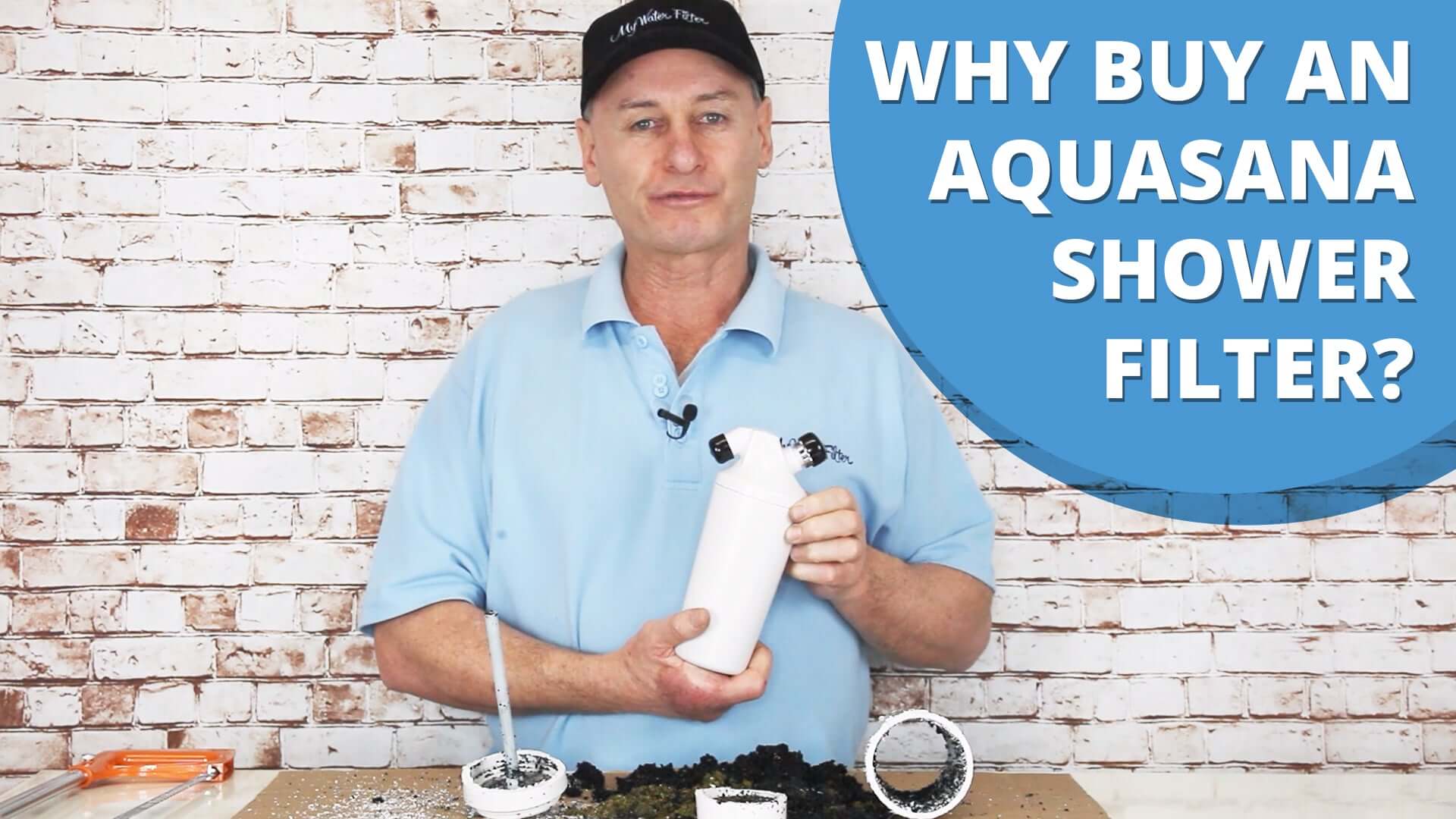 Rod demonstrates an Aquasana AQ-4125C Premium Shower Filter Chloramine Removal Replacement Cartridge with the text "Why choose an Aquasana shower filter?" against a brick wall background, emphasising its advantages for healthier hair and efficient chloramine removal.