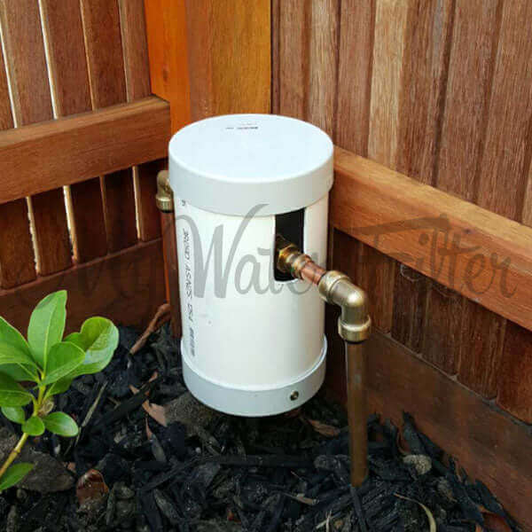 The Grander Whole House System water filtration unit, named Grander, is installed on a wooden fence