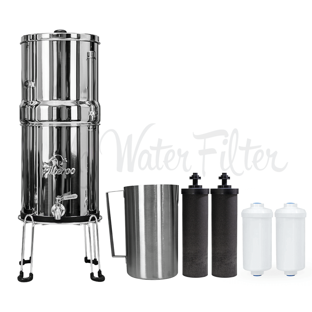 Filteroo® Stainless Steel Gravity Water Filter system sits on a stainless steel stand with its tap. On the right are the stainless steel jug, two black carbon block cartridges,  and two white Max Fluoride cartridges
