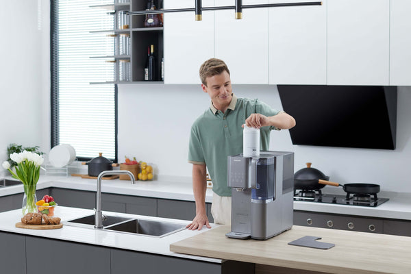 Man using Philips Aquaporin Reverse Osmosis Water Station ADD6921DG/79 in kitchen for fresh water.