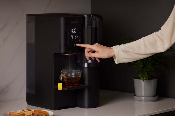 Person using Philips Aquaporin Water Station ADD6920BK/79 to heat water for tea.