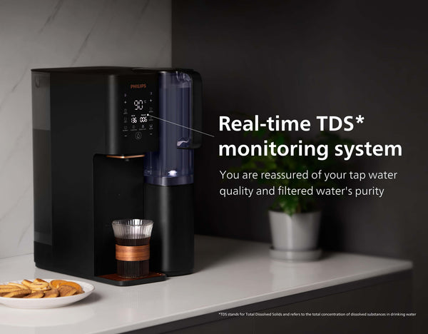 Real time TDS monitoring system with the Philips Aquaporin Reverse Osmosis Water Station ADD6920BK/79, black, on counter with glass of water and cookies.
