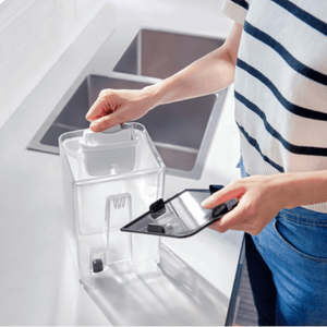 A person organizes a transparent kitchen container beside the sink, enjoying the efficient operation of the Philips ADD5910M/79 Compact Water Station with Micro X-Clean Filtration.