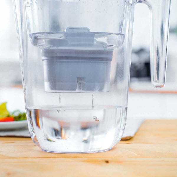 Philips water pitcher featuring a Philips Micro X-Clean Carbon Filter AWP211, partially filled with water, resting on a wooden table.