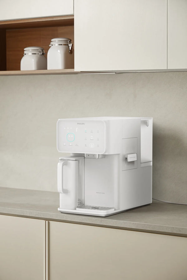 White Philips water station on a kitchen counter under wall cabinets, with the water jug on the left and ice drawer on the right.
