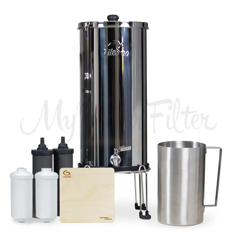 Filteroo® Superoo Stainless Steel Gravity Water Filter System with the two white Max Fluoride removal cartridges and two black carbon block cartridges alongside a wooden board known as the Grander Revitalising Board and a stainless steel jug