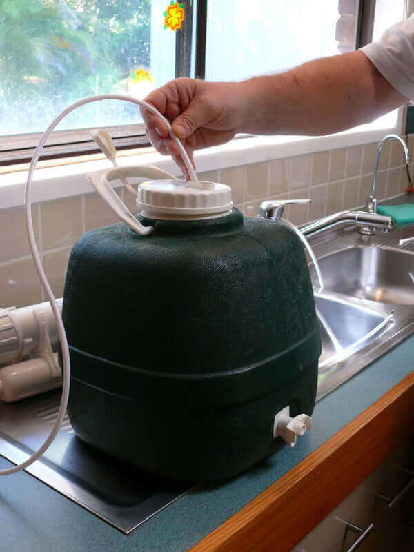 A person connects a tube to the 3 Stage Portable Reverse Osmosis Water Filter System on a kitchen counter.