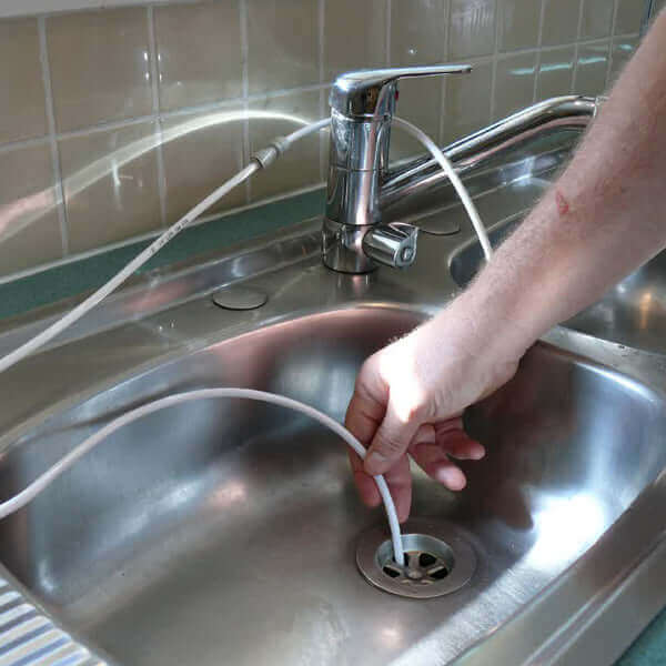 Hand holding a white cord over a kitchen sink with a silver faucet, highlighting the 3 Stage Portable Reverse Osmosis Water Filter System with Alkalising Filter.