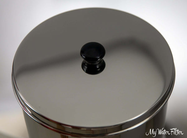 A close up of Phoenix lid made from stainless steel, featuring a light-reflective surface and a black handle.