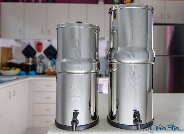 Two Phoenix Stainless Steel Gravity Water Filters on a kitchen counter, surrounded by cabinets and other kitchen items.