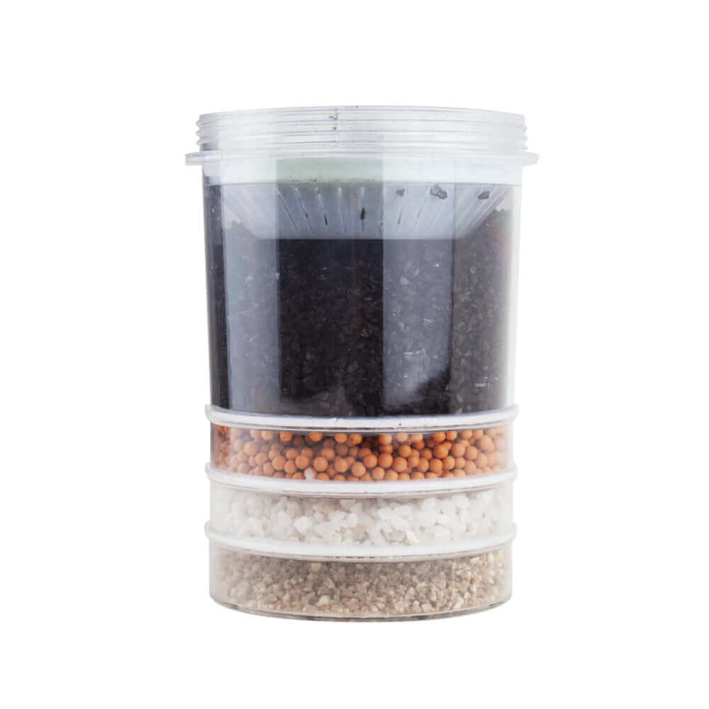 Transparent filter featuring the Carbon Multi Media Water Filter Replacement Cartridge, containing charcoal, orange beads, white sand, and brown granules for use in the 6 Stage Multi Use pH Elevation Benchtop Gravity Water Filter.