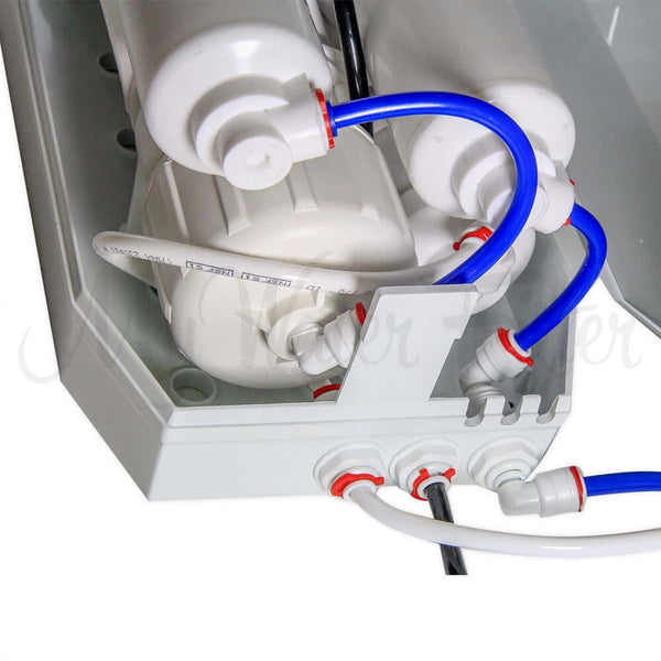 Close-up of the RO 4000 Benchtop Reverse Osmosis Water Filter System with white and blue tubing connected to cylindrical components, including an alkaline cartridge.